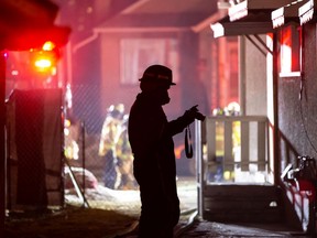 An Edmonton Fire Rescue Service investigator takes photos as firefighters extinguish a fire in a home on 95 Street near 111 Avenue in Edmonton, on Wednesday, Jan. 20, 2021.