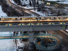 Walkers get fresh air while LRT train riders head home from work over the Dudley B. Menzies LRT Bridge as the weather cools in Edmonton, on Friday, Jan. 22, 2021.