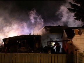 Edmonton Fire Rescue Service firefighters check for hot spots as they extinguish a blaze in a mobile home in Westview Village at Westview Close and Westview Crescent in Edmonton, on Monday, Jan. 25, 2021.