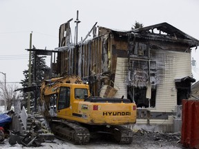 Fire investigators search the aftermath of a duplex fire for the bodies of a a teenager and a woman on Wednesday, Jan. 27, 2021 in Evansburg, Alberta.