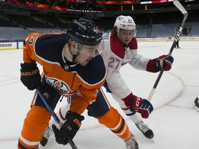 Edmonton Oilers Devin Shore (14) and Montreal Canadiens Alexander Romanov (27) battle at Rogers Place on Saturday, Jan. 16, 2021.