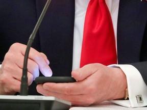 U.S. President Donald Trump taps the screen on a mobile phone at the approximate time a tweet was released from his Twitter account, during a roundtable discussion on the reopening of small businesses in the State Dining Room at the White House in Washington, U.S., June 18, 2020.