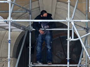 A man clings to scaffolding outside the Alberta government McDougall Centre in downtown Calgary on Thursday, Jan. 28, 2021. The man was brought down without incident.