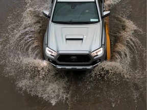 A driver of a Toyota Tacoma navigates flooding on Whitemud Drive under the 106 Street bridge during a thunderstorm in Edmonton on July 16, 2020. Edmonton received the highest score for flood preparedness of major Canadian cities in a study from the Intact Centre on Climate Adaptation.