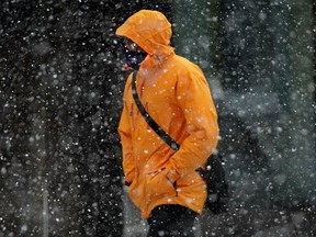 A pedestrian crosses the street during a heavy snowfall in downtown Edmonton on Tuesday February 2, 2021.