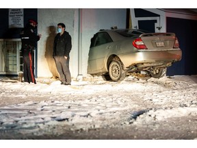 An Edmonton Police Service officer speaks to a bystander after a driver of a Toyota Camry lost control and hit a suite in the Juliette Manor apartment building at 119 Street and 103 Avenue in Edmonton, on Wednesday, Feb. 3, 2021. Photo by Ian Kucerak