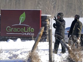 Two men keep unwelcome visitors from entering the property at  GraceLife Church in Parkland County, just east of Edmonton, on Sunday February 7, 2021. The church has defied government pandemic restrictions multiple times and held a church service on this day.