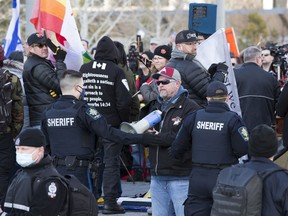 Police line up between counter-protesters and anti-mask protesters during a rally at the Alberta legislature on Saturday, Feb. 20, 2021.