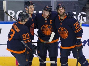 Edmonton Oilers Connor McDavid (97) celebrates his hat trick goal against the Calgary Flames with teammates Ryan Nugent-Hopkins (93), Jesse Puljujarvi (13) and Darnell Nurse (25) during second period NHL action on Saturday, Feb. 20, 2021 in Edmonton.