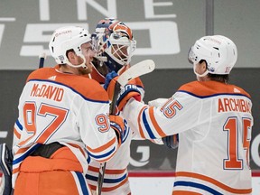 Edmonton Oilers forward Connor McDavid (97) and goalie Mike Smith (41) and forward Josh Archibald (15) celebrate their victory against the Vancouver Canucks at Rogers Arena on Feb. 25, 2021.