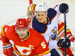 Calgary Flames' Mark Giordano and Jesse Puljujarvi of the Edmonton Oilers fight for position in front of Flames goaltender goalie David Rittich in Calgary on Friday, Feb. 19, 2021.