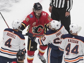 The Calgary Flames’ Matthew Tkachuk roughs it up with Edmonton Oilers Kris Russell (4), Tyler Ennis (63) and Zack Kassian (44) during an exhibition game at Rogers Place on July 28, 2020.