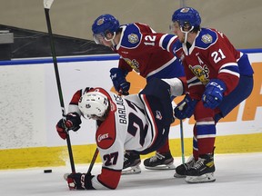 Edmonton Oil Kings Liam Keeler (12) and Jake Neighbours (21) upset Lethbridge Hurricanes Logan Barlage (27) at Rogers Place in Edmonton on Friday, Feb. 26, 2021.