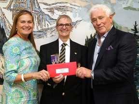 File photo of No Stone Left Alone Memorial Foundation President Maureen Bianchini-Purvis and No Stone Left Alone Memorial Foundation Marketing/Media Director Randall Purvis and Royal Canadian Legion Poppy Fund - Edmonton's Chief Administrative Officer Gwen Beasley with a cheque for $10,000, in Edmonton Alta., on Monday Aug. 25, 2014.
