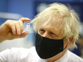 Britain's Prime Minister Boris Johnson poses with a vial of the Oxford/AstraZeneca vaccine as he visits a vaccination centre at Cwmbran Stadium in Cwmbran, south Wales on Feb. 17, 2021. The U.K. has inoculated 22 million residents since December, compared to Canada's 2.2 million. Part of their success is linked to the data-driven Foundry information system, which Alberta will be adopting.
