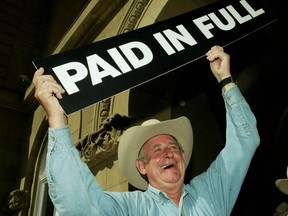 Then-Alberta Premier Ralph Klein held up a "paid in full" sign after announcing July 12, 2004 that the province's debt of $3.7-billion had been paid off in full ahead of schedule. Klein made the announcement following his annual Stampede breakfast at the McDougall Centre in Calgary.