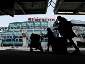 The airport hotel is shown as people walk outside with their luggage at Pearson International Airport during the COVID-19 pandemic in Toronto on Tuesday, February 2, 2021.