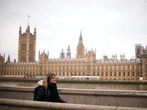 A woman walks along the River Thames with the Houses of Parliament in the background, amid the coronavirus disease (COVID-19) outbreak, in London, Britain February 22, 2021.