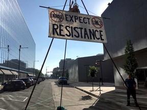 An activist opposing the Enbridge Line 3 oil pipeline, dangles from a steel structure erected outside the Minnesota Public Utilities Commission office in St. Paul, Minnesota in 2018. While the Canadian portion is complete, Enbridge has run into repeated obstacles in this state, where reviews have lasted for about five years.