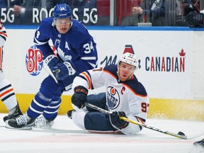 Connor McDavid (97) of the Edmonton Oilers battles for the puck against Auston Matthews (34) of the Toronto Maple Leafs during the first period an NHL game at Scotiabank Arena on March 29, 2021 in Toronto.