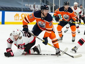 Edmonton Oilers’ Connor McDavid (97) battles Ottawa Senators’ Erik Brannstrom (26) at Rogers Place in Edmonton on Monday, March 8, 2021.