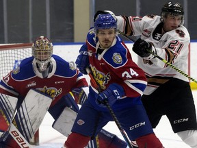 The Edmonton Oil Kings' Kaid Oliver (34) battles the Calgary Hitmen's Riley Fiddler-Schultz (21) in front of goaltender Sebastian Cossa (33) during first period WHL action in Edmonton on Friday, March 26, 2021.