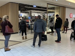 Shoppers line up at a store in Southgate Centre Mall on Friday, Dec. 11, 2020 in Edmonton.  With new COVID-19 restrictions  going into effect Sunday in Alberta some shoppers are taking advantage of the last days of looser retail rules