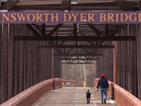 A man and his dog cross the Ainsworth Dyer Bridge between Rundle Park and Gold Bar Park as snow falls in Edmonton, on Friday, Feb. 26, 2021.