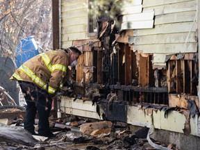 An Edmonton Fire Rescue Services firefighter checks a fire damaged home as the crew packs up equipment after extinguishing an early morning fire at 104 Street and 133 Avenue in Edmonton, on Thursday, March 18, 2021.
