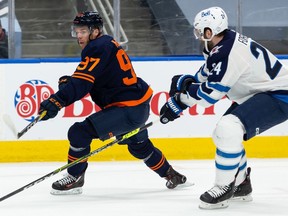 Edmonton Oilers' Connor McDavid (97) shoots on Winnipeg Jets' goaltender Connor Hellebuyck (37) during first period NHL action at Rogers Place in Edmonton, on Saturday, March 20, 2021.