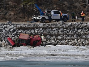 A driver was extricated from this sweeper after it tumbled down the westside embankment, landing on the ice of the North Saskatchewan River near the Fort Edmonton Footbridge in Edmonton, March 31, 2021. City crews are waiting for a larger tow truck to be brought in to lift the machine out.
