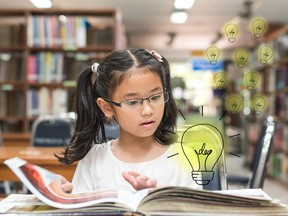 Innovative creative idea for copyrights law concept with kid surprised reading book with lightbulb in library