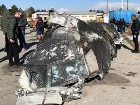 This handout photograph taken and released on Jan. 11, 2019, by The National Security and Defence Council of Ukraine, shows people standing and analyzing the fragments and remains of the Ukraine International Airlines plane Boeing 737-800 that crashed outside the Iranian capital Tehran on Jan. 8, 2020.