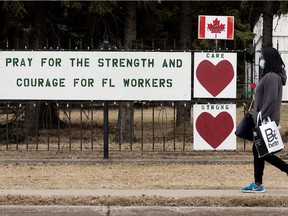 A pedestrian, wearing a mask to protect against COVID-19, walks past signs of support for frontline workers outside Sisters Of The Precious Blood, 9415 165 St., in Edmonton on Tuesday, March 23, 2021.