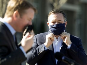 Health Minister Tyler Shandro, left, and Premier Jason Kenney adjust their face masks as they take part in a news conference where they provided an update on the distribution of COVID-19 vaccines through participating community pharmacies in Edmonton on March 18, 2021.