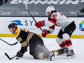 New Jersey Devils defenseman Dmitry Kulikov (70) checks Boston Bruins left wing Nick Ritchie (21) during the first period at TD Garden on March 30, 2021.