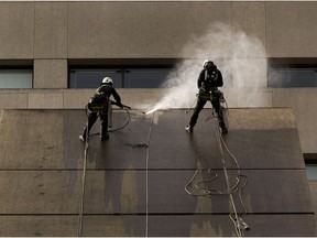 Workers power wash the walls of the Edmonton Law Courts building on April 9, 2021.