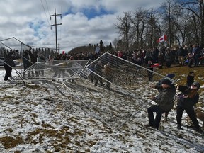 A few in attendance tried to rip down the fencing as police stand their ground while a crowd of about 400 gathered outside GraceLife Church on the first Sunday after the closure west of the Edmonton city limits, April 11, 2021.