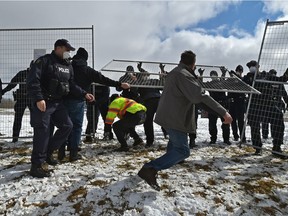 A few in attendance tried to rip down the fencing as police stand their ground while a crowd of about 400 gathered outside GraceLife Church on the first Sunday after the closure west of the Edmonton city limits, April 11, 2021.