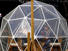 Two diners enjoy lunch inside a heated dining bubble on the sidewalk outside the Tiramisu Bistro in Edmonton on Monday April 12, 2021. The Alberta government imposed new COVID-19 health restrictions in the province last Friday prohibiting all restaurant indoor dining.