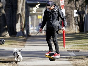 Ryan Parker takes his dog "Finn" (Havanese Pomeranian) for a walk while riding his electric one-wheeled skateboard in Edmonton on Thursday April 15, 2021.