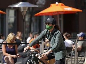 A cyclist pedals past outdoor diners on 104 Street in downtown Edmonton on Saturday April 17, 2021, where the street was closed to motor vehicles to allow restaurants to serve patrons outside on the street during the COVID-19 pandemic.