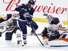 Edmonton Oilers defenseman Tyson Barrie (22) and Winnipeg Jets left wing Kyle Connor (81) jump from the puck in front of Edmonton Oilers goaltender Mike Smith (41) in the second period at Bell MTS Place on April 17, 2021.