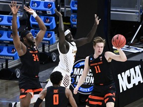 Oregon State Beavers guard Zach Reichle (11) passes the ball against Loyola University of Chicago Ramblers forward Aher Uguak (middle), who is swarmed by Oregon State forward Rodrigue Andela (34) and guard Gianni Hunt (0) during the Sweet 16 of the 2021 NCAA tournament at Bankers Life Fieldhouse in Indianapolis on March 27, 2021.