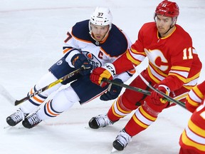 Calgary Flames forward Mikael Backlund and Edmonton Oilers captain Connor McDavid jostle for position at the Scotiabank Saddledome in Calgary on Saturday, April 10, 2021.