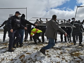 Police erect fencing that had been torn down by people gathered outside the GraceLife Church near Edmonton on April 11, 2021.