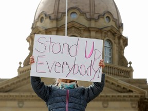 A young girl (with her mother not in frame) protests the Province's draft K-6 curriculum, outside the Alberta Legislature, in Edmonton Thursday April 1, 2021.