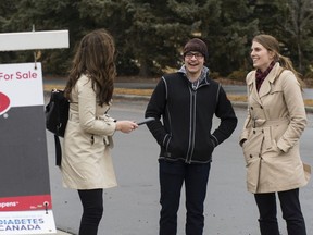 Realtor Deidre Harrison with Liv Real Estate talks with home buyers Brandyn Baranitsky  and Samantha Hinz outside a home in Edmonton.