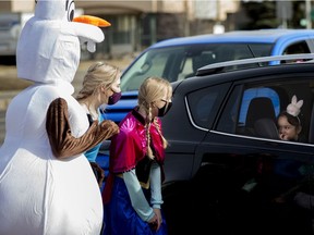 A shy young girl visits with Disney characters as her family attends a drive-thru Easter celebration at Celebration Church – Central, 7215 Argyll Road, in Edmonton Saturday April 3, 2021.