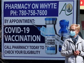A pedestrian makes their way past a sign advertising COVID-19 vaccinations at a pharmacy in Edmonton on Monday, April 12, 2021.